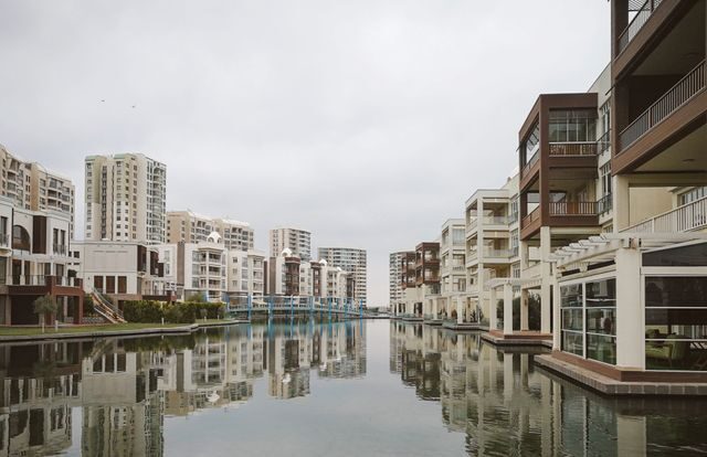 Modern residential buildings reflecting in a tranquil urban canal.